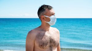 Hombre con mascarilla en la playa verano España